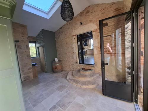 a bathroom with a glass door and a stone wall at Les Mas d Olema in Puy-lʼÉvêque