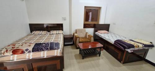a bedroom with two beds and a chair in it at Om Hotel & Lodge in Baharāgora