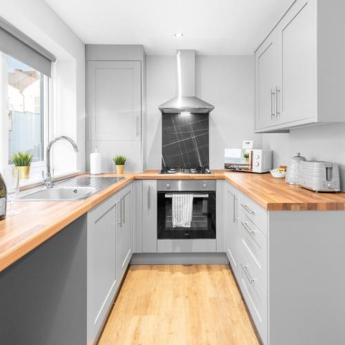 a kitchen with white cabinets and wooden counter tops at Modern 2 Bed Apartment - 2 Parking Spaces - Sleeps 3 - Netflix 1BS in Amblecote