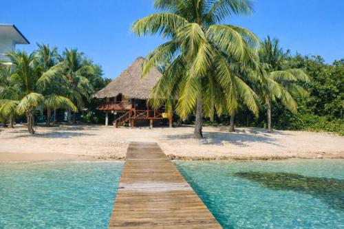 a wooden pathway leading to a resort on a beach at Kin Resort Lodge in Maya Beach