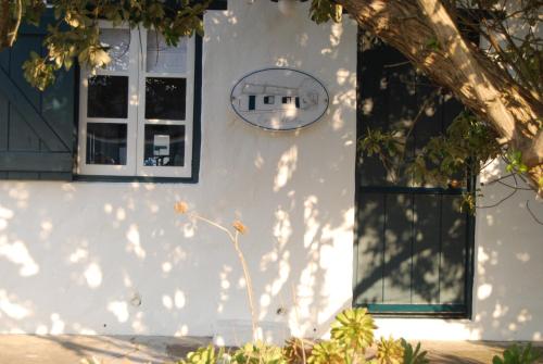 a white house with a window and a door at Cape Creek Cottage, Luxury Coastal Getaway in Struisbaai
