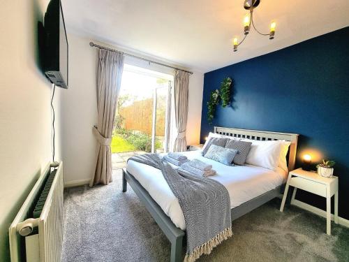 a bedroom with a bed with a blue wall at Spacious 4 Bed Family Home with Private Garden & Free Parking - Hamilton in Leicester