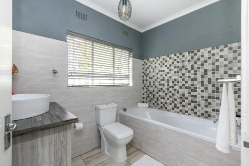 a bathroom with a toilet and a tub and a sink at Mistica on St James in Johannesburg