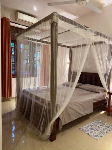 a bedroom with a canopy bed with mosquito nets at THC - Tropical Hideaway Ceylon in Talpe