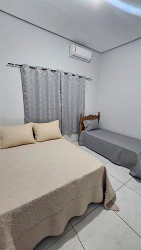 a bedroom with two beds and a window at Casa próxima à Praia do Cerrado e centro in Goianésia