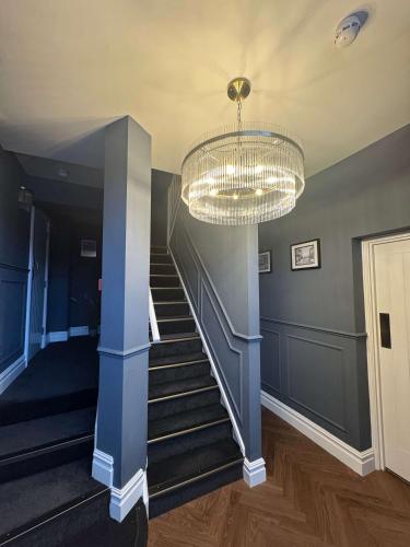 a hallway with a staircase with a chandelier at The Royal Keep Hotel in Dudley in Dudley