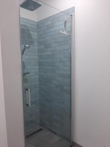 a glass shower with blue tiles in a bathroom at L'Ultra Pause au cœur du Viroin in Olloy-sur-Viroin