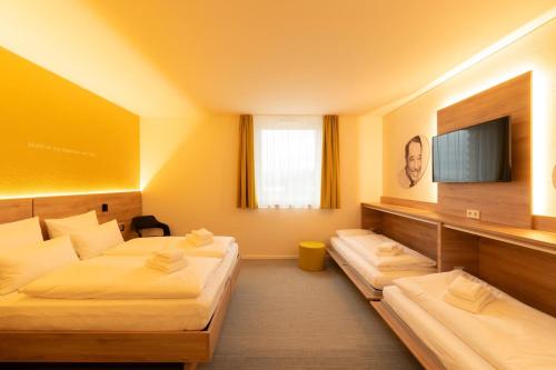 a hotel room with two beds and a flat screen tv at BDB-Kulturhotel in Staufen im Breisgau