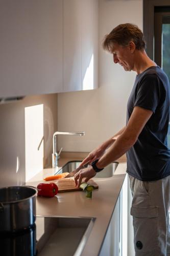 a man cutting up vegetables on a cutting board in a kitchen at Modern apartments in one building, in the heart of Girona in Girona