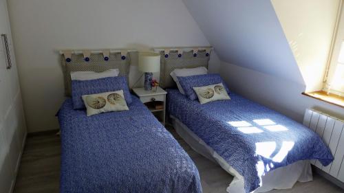 two beds in a small room with blue comforter at Les Guédrils in Genêts