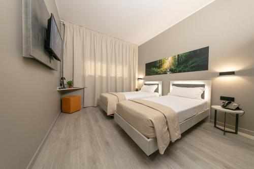 a bedroom with two beds and a flat screen tv at Break Hotel in Ospedaletto Lodigiano