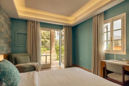 a bedroom with a bed and a desk and a window at Zeus Eretria Resort in Eretria