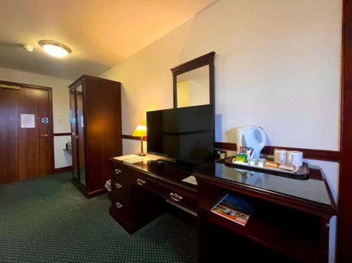 a hotel room with a television and a desk with a mirror at The Weigh Inn Hotel & Lodges in Thurso