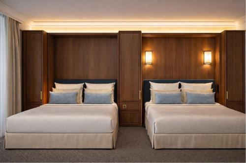 two beds in a room with wooden walls and lights at Hotel Saint Cyr Etoile in Paris