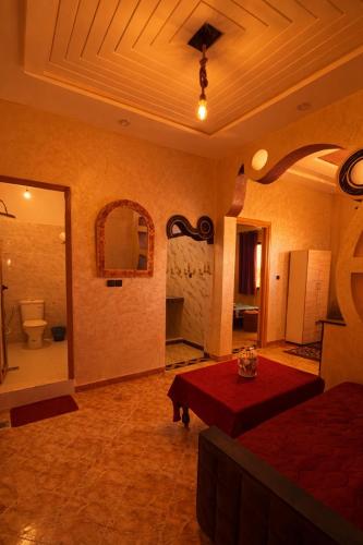 a living room with a table and a bathroom at Riad Mifis in Rissani