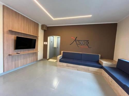 a living room with a blue couch and a tv at Astor Suítes - Unicamp in Campinas