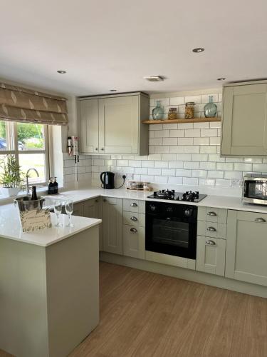 a kitchen with white appliances and white cabinets at LODGE Nuthatch in Droitwich