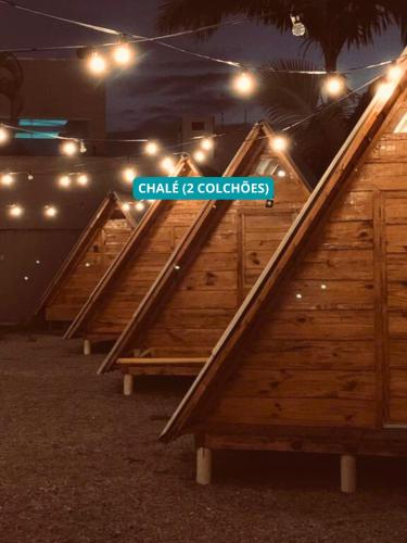 a row of wooden benches with a sign that reads chalk c colleges at Hostel Costa Terral in Matinhos