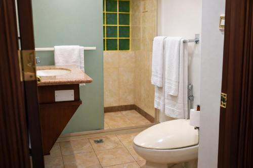 a bathroom with a toilet and a shower and a sink at Sand Rose Hotel Apartments in Al Khobar