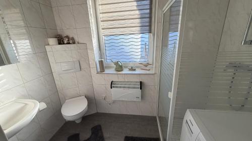a white bathroom with a toilet and a sink at Bitterfeld Apartment modern & gemütlich in Holzweißig