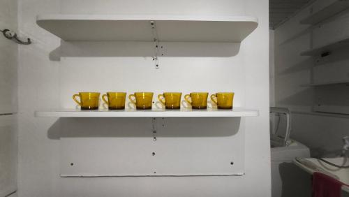 four yellow bowls on a shelf in a room at Sobrado há 7 quadras da praia in Matinhos