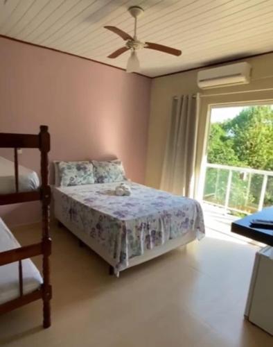a bedroom with a bed with a ceiling fan and a window at Pousada Colibri in Trindade