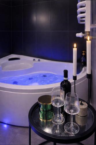 a bath tub with a table with wine glasses and candles at EUROPA22 Apartament z JACUZZI w samym sercu miasta Tomaszów Maz - balkon z widokiem na park i fontanny Szybkie zameldowanie od 13 in Tomaszów Mazowiecki