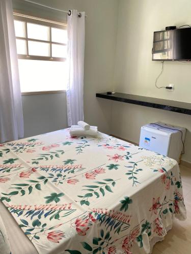 a bedroom with a bed with a flowered blanket at Pousada Colibri in Trindade