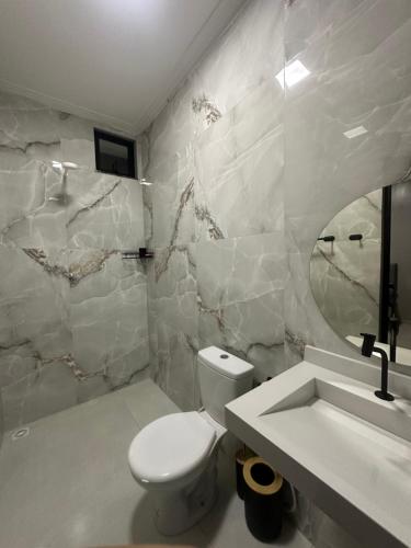 ein Badezimmer mit weißer Toilette und Waschbecken in der Unterkunft DeckMC in Itarema