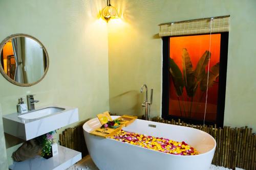 a bathroom with a tub with a sink and a mirror at Ruby's Home- Doc Let's House in Ngân Hà