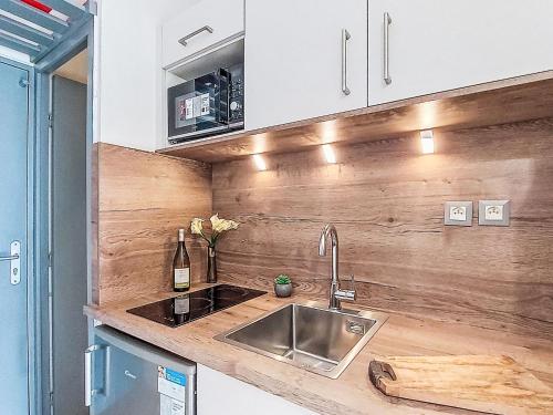 a kitchen with a sink and a wooden wall at Studio Les Olympiades-28 by Interhome in Val Thorens