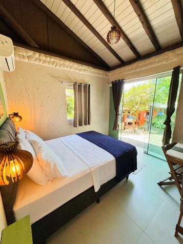 a bedroom with a bed and a large window at Hostel Antônio Pescador - Centro da Guarda do Embaú in Guarda do Embaú