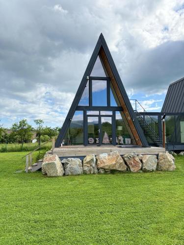 a house with a triangular roof and some rocks at AnturAge Concept in Novaci-Străini