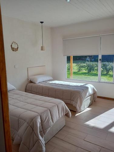 two beds in a white room with a window at Le Clos La Perdiz in Pigüé