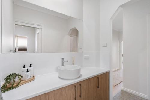 a white bathroom with a sink and a mirror at The Water House - Lakeside Serenity & Modern Comfort in Encounter Bay