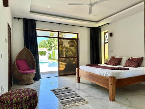 a bedroom with a bed and a chair and a window at Villa Samara - 10p - 5bdr - Diani Beach - Piscine in Magutu