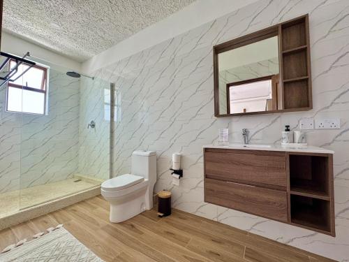 a bathroom with a toilet and a sink and a mirror at Villa Samara - 10p - 5bdr - Diani Beach - Piscine in Magutu