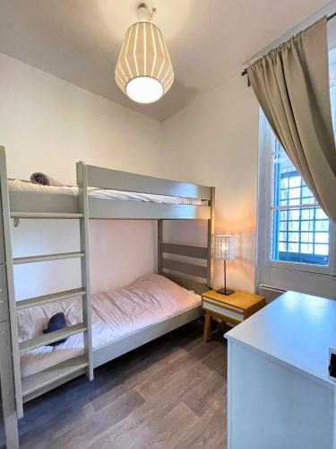 a bedroom with two bunk beds and a table at Villa LES MYRTILLES in Cabourg