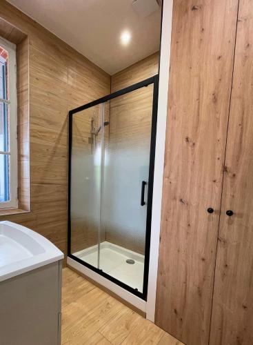 a glass shower in a bathroom with wooden walls at Villa LES MYRTILLES in Cabourg