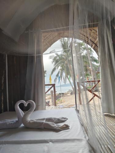 two swans sitting on a bed in front of a beach at EL-NARA SEASIDE Beach Resort in El Nido