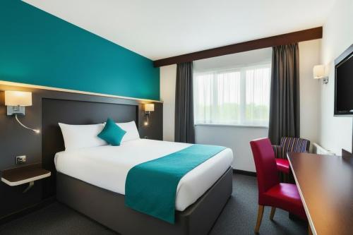 a hotel room with a large bed and a desk at Ramada Milton Keynes in Milton Keynes