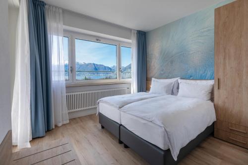 a bedroom with a bed and a large window at Hotel Village Campofelice in Tenero
