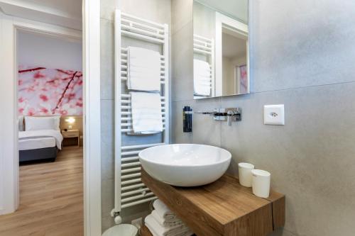 a bathroom with a white sink and a bedroom at Hotel Village Campofelice in Tenero