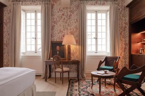 a bedroom with a bed and a desk and two windows at Les Sources de Vougeot in Vougeot