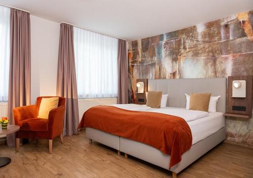 a hotel room with a bed and a chair at Art Hotel Aachen in Aachen