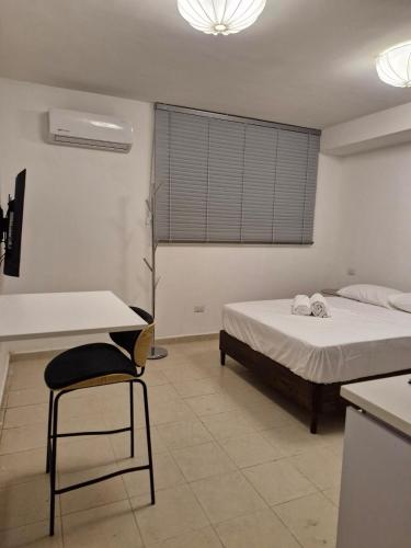 a bedroom with a bed and a table and a chair at Loft 204 - H54 WAIWA HOST in Bucaramanga