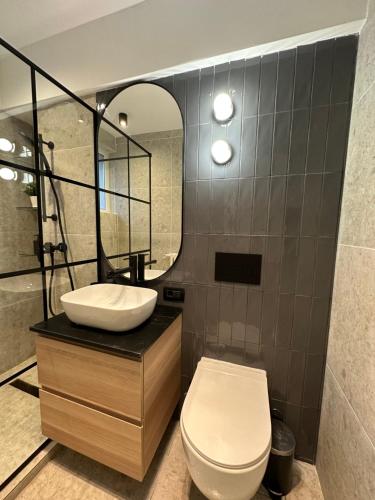 a bathroom with a toilet and a sink and a mirror at Luxury by Magic Apartments in Bucharest
