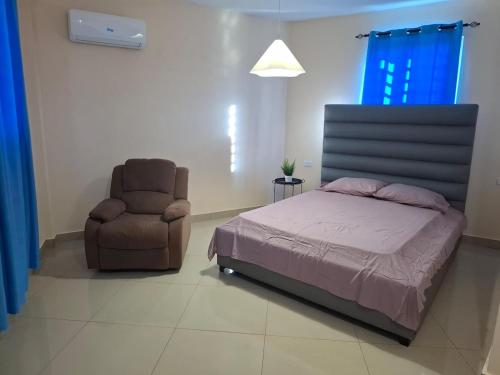a bedroom with a bed and a chair at Doña Minda Home in Naiboa