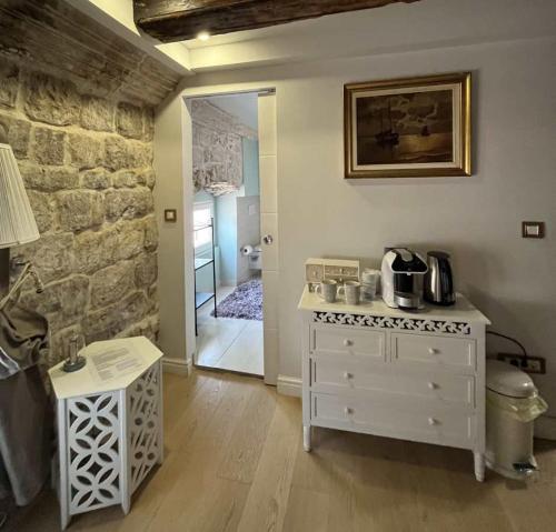 a kitchen with a white dresser and a stone wall at Dubrovnik Deluxe Rooms in Dubrovnik