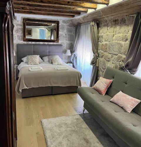 a bedroom with a bed and a couch and a mirror at Dubrovnik Deluxe Rooms in Dubrovnik